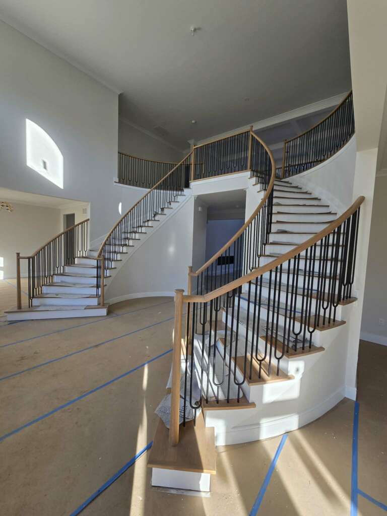 Curved staircase with iron balustrades and polished wood handrail